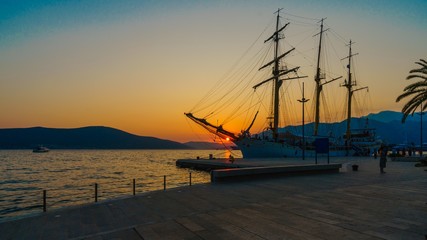 Three-masted yacht in port amid sea sunset