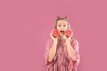 Surprised young woman with grapefruit on color background. Diet concept