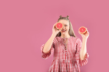 Young woman with grapefruit on color background. Diet concept