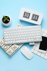 Computer keyboard with notebook, mobile phone, alarm clock and noughts-and-crosses game on color...