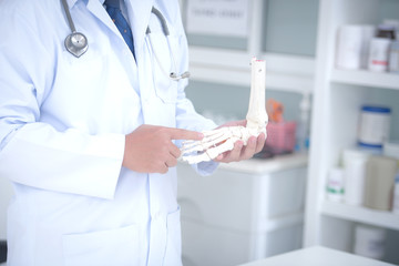 Orthopedic doctor in his office with the patient and the foot model orthopedic doctor in his office and the foot model who holds the ankle bone in the doctor's office
