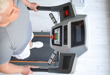 Senior man training on treadmill in gym, top view
