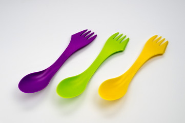 Tourist plastic fork spoon in different colors, photographed large on a white background.