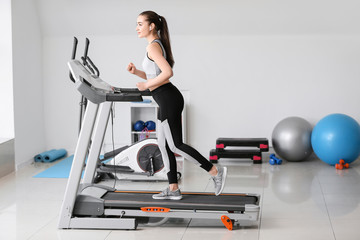 Fototapeta premium Sporty young woman training on treadmill in gym