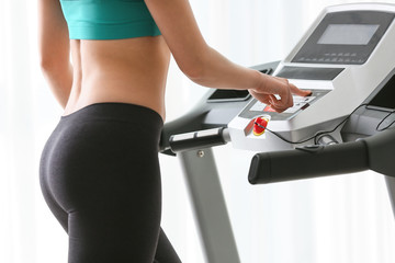 Fototapeta na wymiar Sporty young woman training on treadmill at home