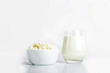 Glass of milk and bowl with homemade cottage cheese on a white background. The concept of healthy dairy products with calcium. Nutrition concept