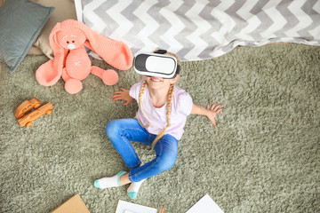 Cute little girl with VR glasses studying at home. Concept of online education