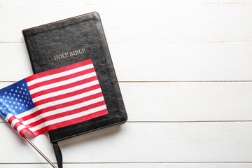 Holy Bible and USA flag on white wooden background