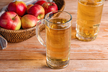 Mugs of apple cider on wooden background