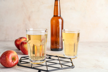 Bottle and glasses of apple cider on table