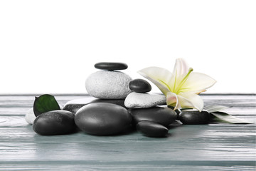 Zen stones and flower on table against white background