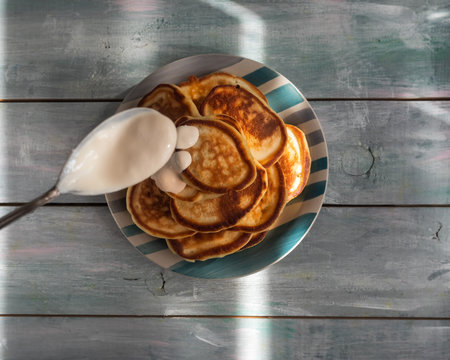 Homemade pancakes with yogurt in a tablespoon on a wooden table
