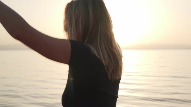 Blonde barefoot girl practice ecstatic dance at sunset seashore