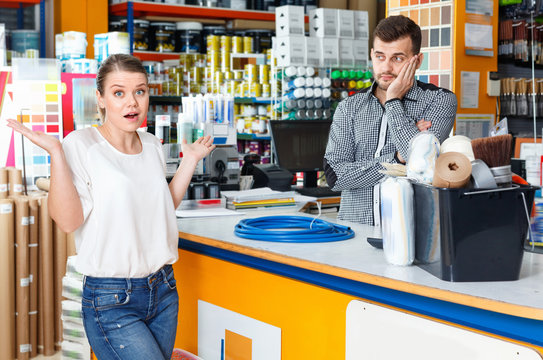Young man seller discussing with upset female customer  in tool-ware shop