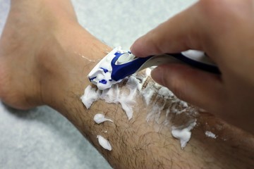 足のムダ毛を剃る男性のクローズアップ