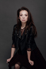 fashion model woman in a black jacket on a gray background