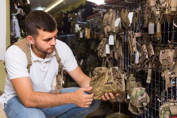 Man choosing holster for gun in military shop