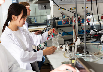 Chinese girl working with reagents in test tubes during chemical experiment