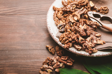 Plate with tasty walnuts on wooden background