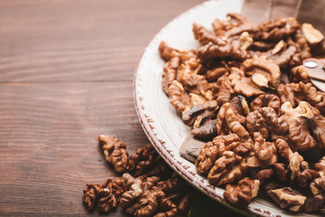 Plate with tasty walnuts on wooden background