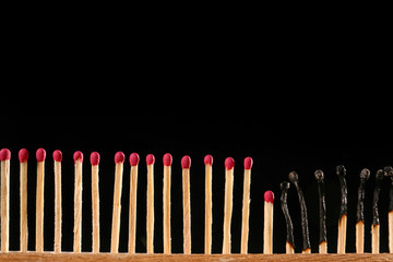 Burnt out and unburnt matches on dark background. Concept of social distance