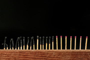 Burnt out and unburnt matches on dark background. Concept of social distance