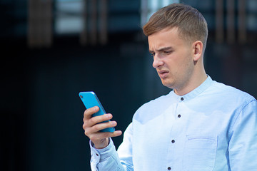 Student Prints Message, displeased European man on his mobile smartphone. Angry young businessman...