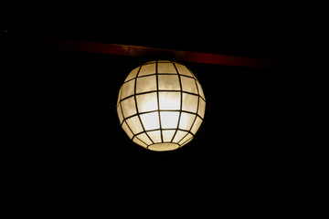 In the dark room the lamp hangs on the ceiling