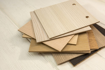 Samples of laminate  planks on white wooden desk for new construction or renovation building