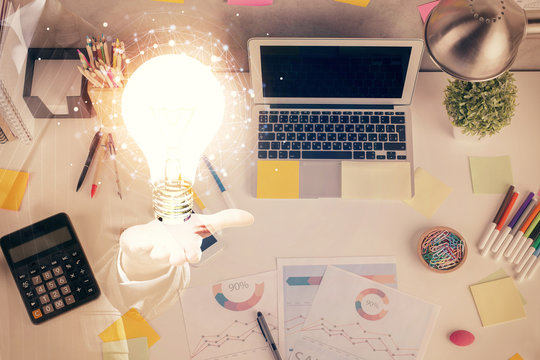 Bulb drawing over computer on the desktop background. Top view. Double exposure. Idea concept.