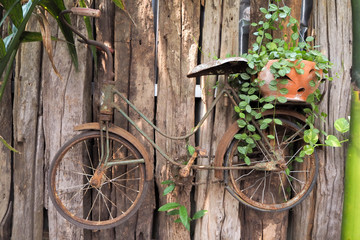 A small antique bicycle used to decorate a wooden fence
