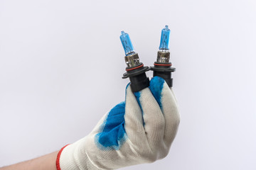 hand in protective glove holding led halogen headlight bulb,isolated. car lighting technology  for...