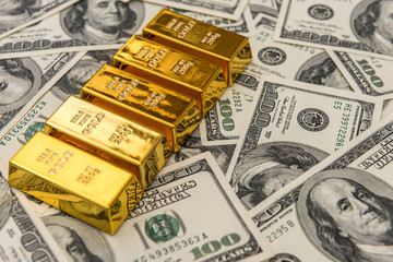  gold bars bullions lying on 100 dollar bills