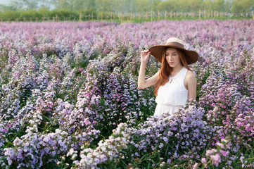 Asian woman with white dress relaxing on Margaret Aster flower field in garde