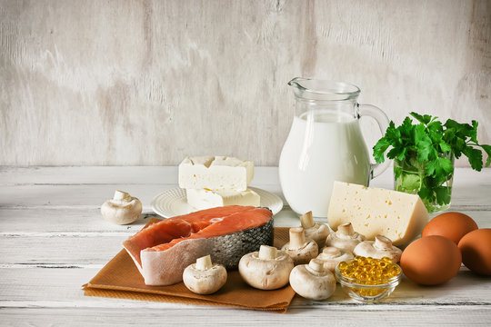 Vitamin D Rich Foods On A White Wooden Table. Natural Sources Of Vitamin D Are Dairy Products, Salmon, Egg, Mushrooms, Parsley, Fish Oil.