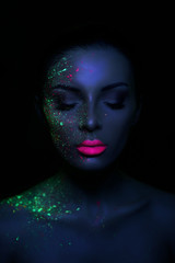 Fashion model woman in neon light bright fluorescent makeup, drop on face. Beautiful model brunette girl colorful make-up, painted skin, body art design ultraviolet