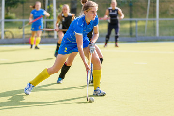Naklejka premium Field hockey female player lead the ball in attack