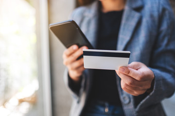 Closeup image of a woman using credit card for purchasing and shopping online on mobile phone