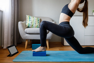 Woman stretching legs by online yoga class at home