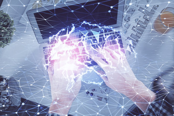 Double exposure of man's hands typing over computer keyboard and brain hologram drawing. Top view. Ai and data technology concept.