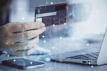 Double exposure of woman on-line shopping holding a credit card and data theme hologram drawing....
