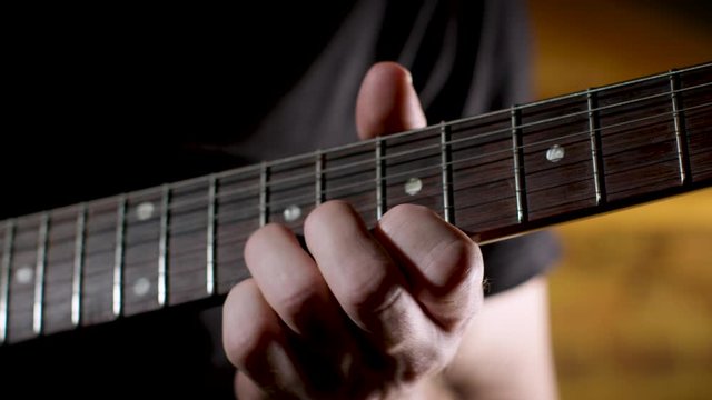 Male guitar player practices a solo on electric guitar, close up on fretboard