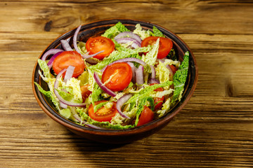Healthy salad with savoy cabbage, cherry tomato, red onion and olive oil on wooden table