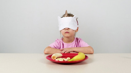 Little girl in a mask tries and guesses banan