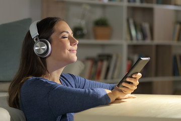 Girl listens music on phone with headphones at night