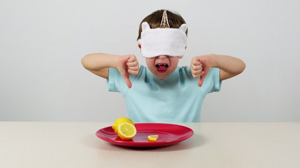 Little boy in a mask tries and guesses lemon and gives thumbs down