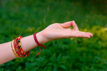 Woman hand in meditation mudra on a green meadow