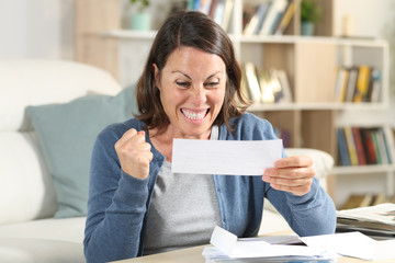 Excited adult woman checking receipts at home