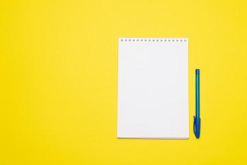 White blank notebook page and pen on yellow background