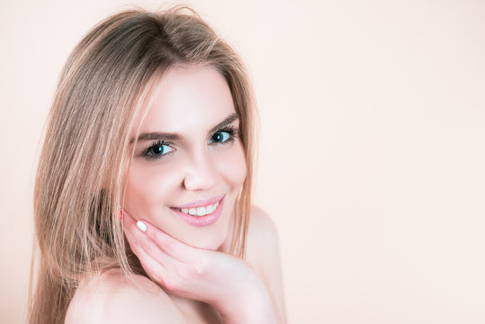 Beutiful female face. Close-up beauty face of young beutiful model woman touching face healthy skin. Natural lips, makeup. Smiling woman.